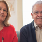 An elderly couple sitting together and smiling indoors